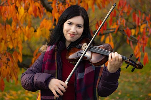 Christine Engelin, Geigenlehrerin in Stuttgart, mit Geige und Bogen vor herbstlichem Laub